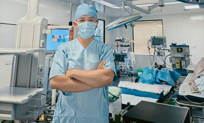 Doctor en quirófano viendo hacia el frente, con uniforme, cofia y cubre bocas