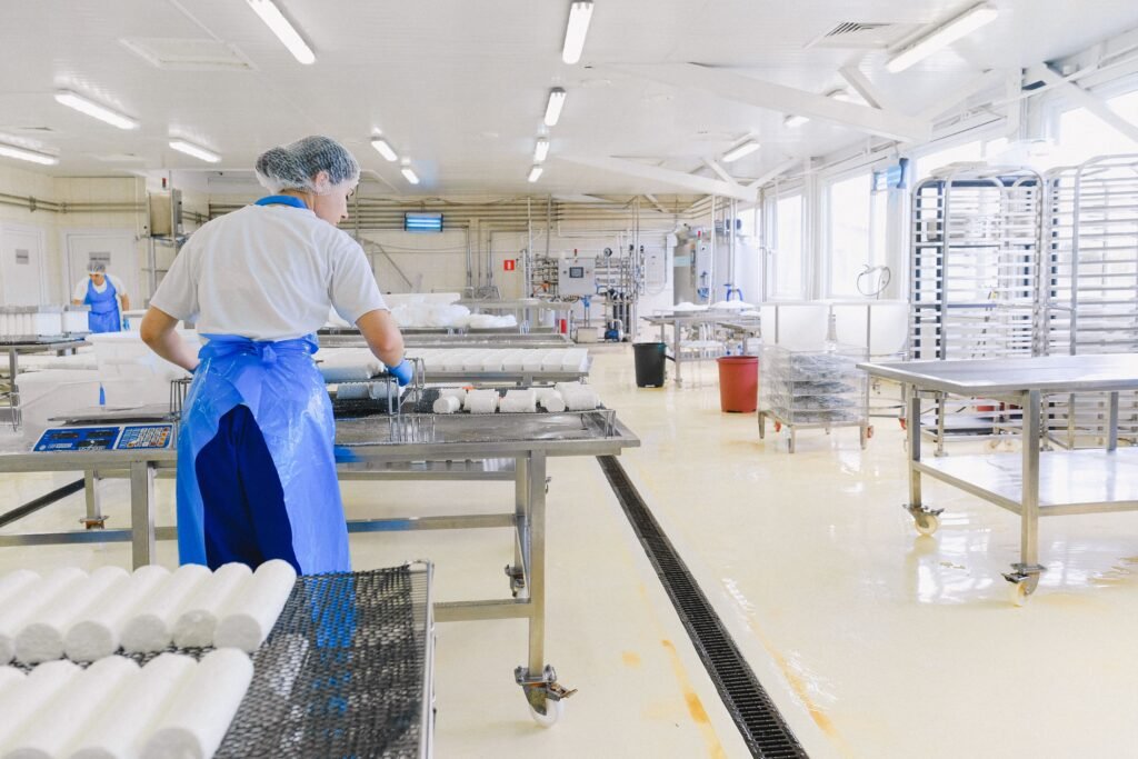 industria de alimentos, una mujer revisando los alimentos que están en una mesa de acero y al fondo más mesas